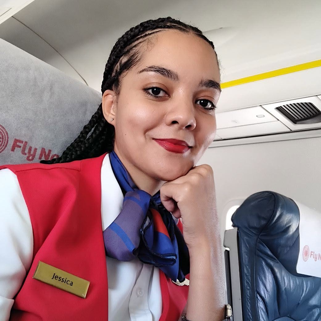 Jessica McLeod seated in a FlyNamibia cabin, wearing her uniform and name badge
